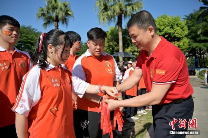 资料图：广西华侨实验高中的教师为高三学子系上红丝带，盼望学子高考必胜。 俞靖 摄