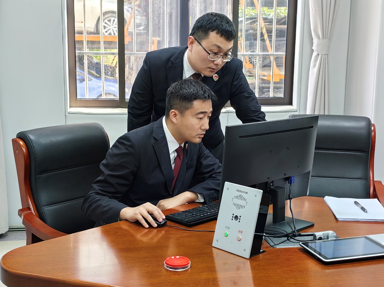 叶涵（左）和同事就一起电信网络诈骗案件研讨分析案情（记者彭照 摄）